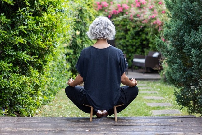 Back view of lady sitting cross legged in garden